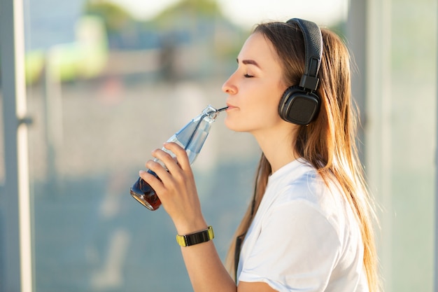 Chica disfruta bebiendo refrescos en escuchar música