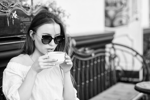 Chica disfruta del café de la mañana Mujer con gafas de sol bebe café al aire libre Chica relajarse en una taza de capuchino de café Dosis de cafeína Café para un día energético exitoso Esperando la fecha Hora del desayuno en la cafetería