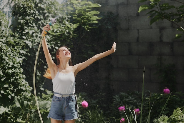 Chica disfrutando del agua en el calor del verano en el jardín.