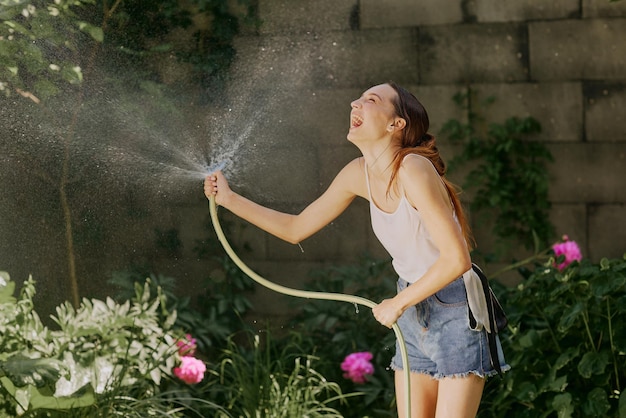 Chica disfrutando del agua en el calor del verano en el jardín.