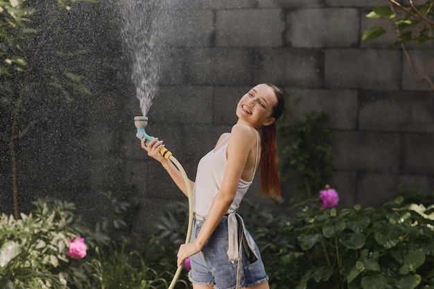 Chica disfrutando del agua en el calor del verano en el jardín.