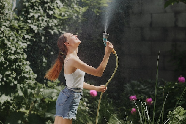 Chica disfrutando del agua en el calor del verano en el jardín.