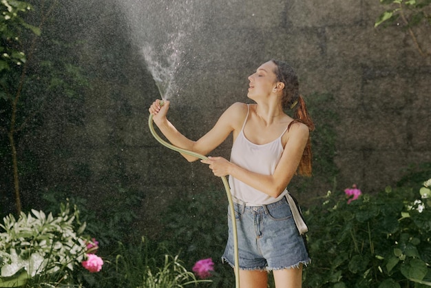 Chica disfrutando del agua en el calor del verano en el jardín.