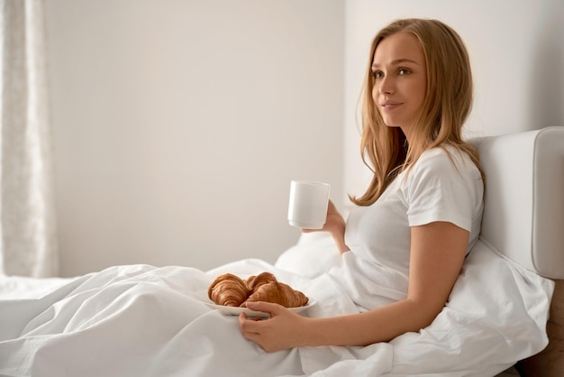 Chica disfrutando del desayuno en la cama