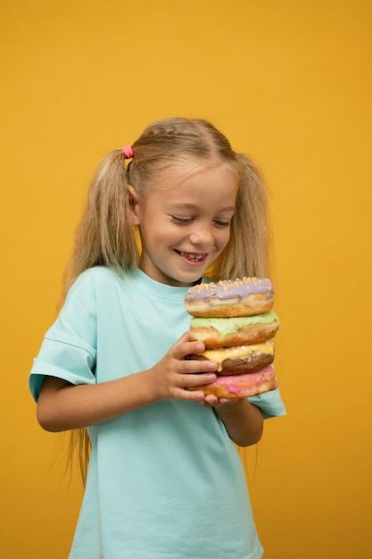 Chica divertida con donuts sobre un fondo amarillo