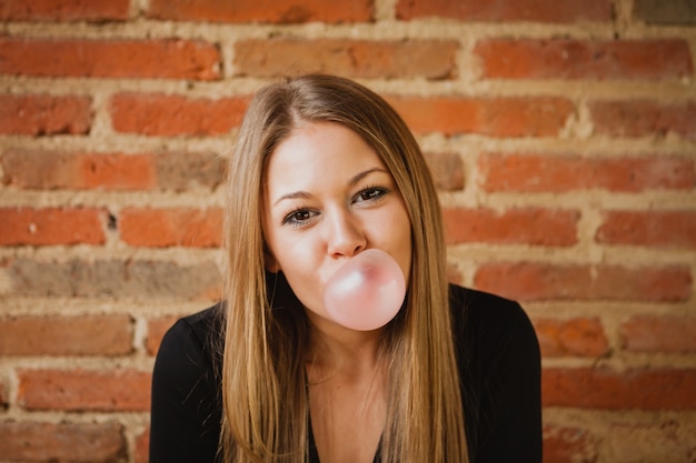 Chica divertida haciendo una pompa con un chicle