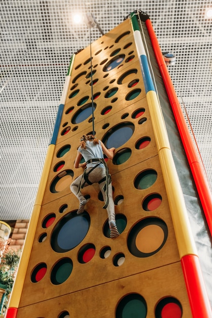 Chica divertida paredes de escalada en el centro de juegos para niños