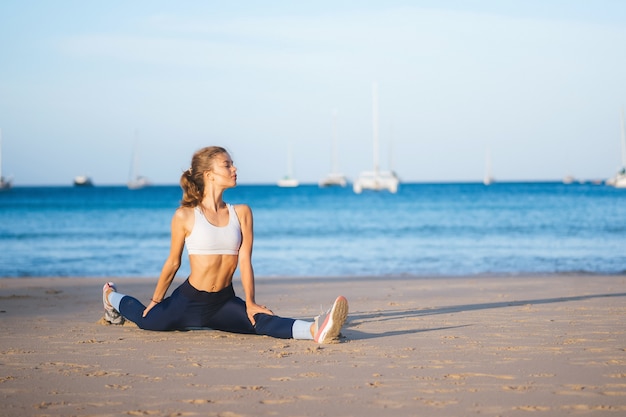 Chica se divide en la playa. Yoga en la playa por la mañana