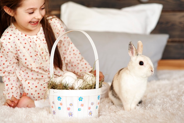 Chica divirtiéndose con conejo en dormitorio