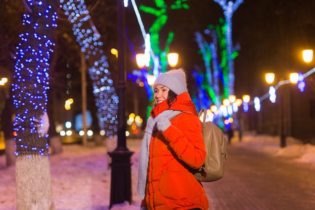 Chica divirtiéndose en la decoración de Navidad luces de la calle joven mujer sonriente feliz vistiendo elegante