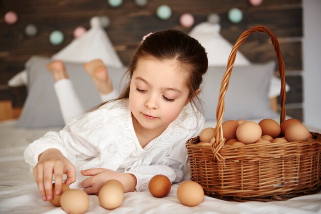 Chica divirtiéndose con huevos en la cama