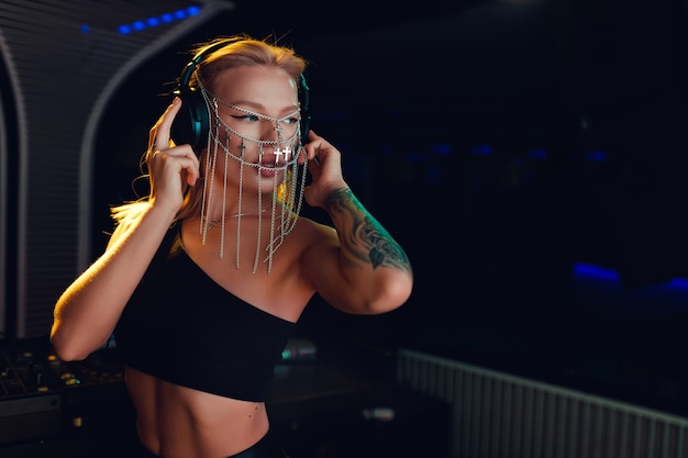 Chica DJ en el mando a distancia con joyas en forma de cadenas en el rostro
