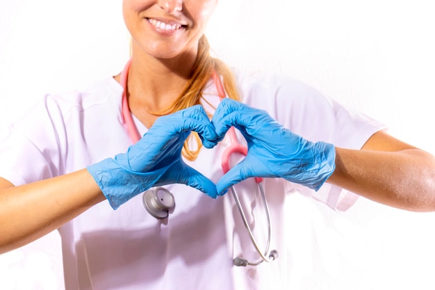 Chica doctora formando un corazón con sus manos y con una cara sonriente Fondo blanco