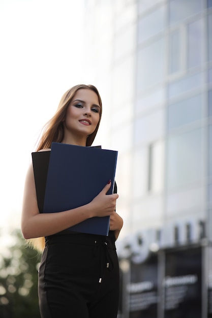 Chica con documentos en una reunión de negocios cerca de un edificio moderno