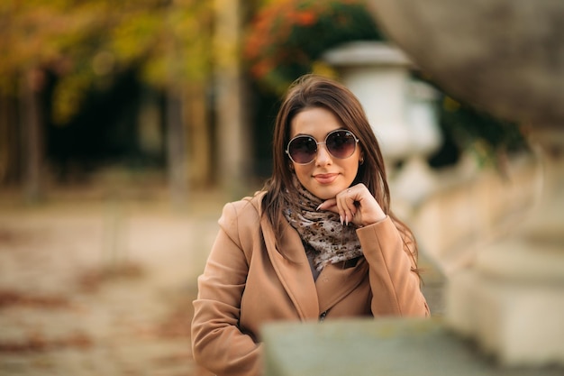 Chica elegante con un abrigo marrón y una bufanda con gafas Maquillaje