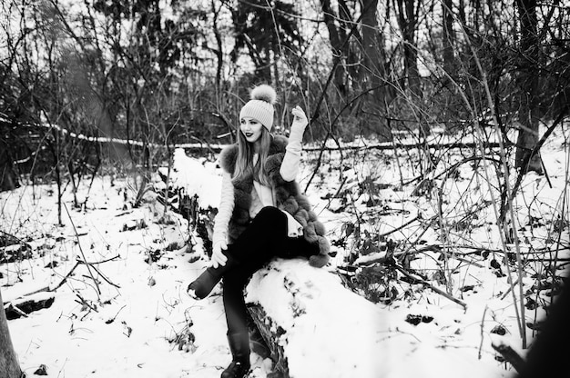 Chica elegante en abrigo de piel y sombreros en el bosque de invierno.