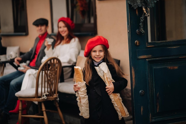 Una chica elegante con baguettes se para cerca de la tienda en el contexto de sus padres