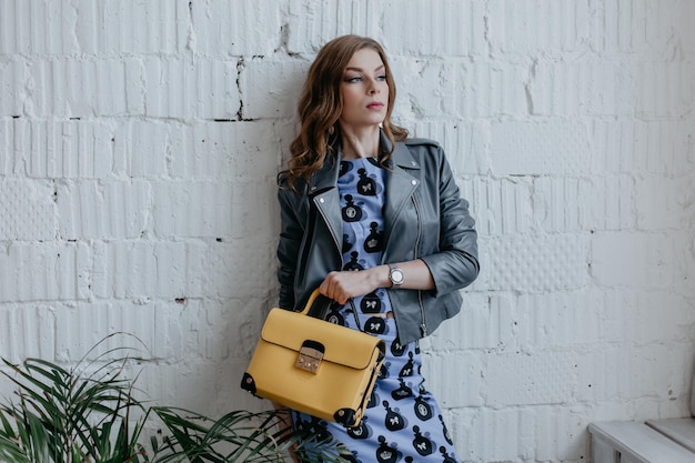 Una chica elegante, hermosa y glamurosa con un vestido azul y una chaqueta de cuero.