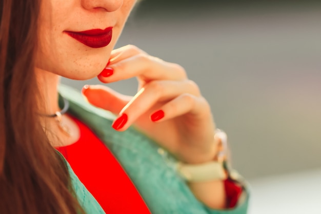 Chica elegante con labios rojos closeup sostiene su mano.