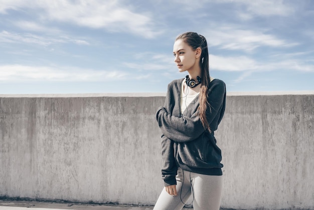 Foto chica elegante y segura posando bajo el cielo azul después de un largo entrenamiento