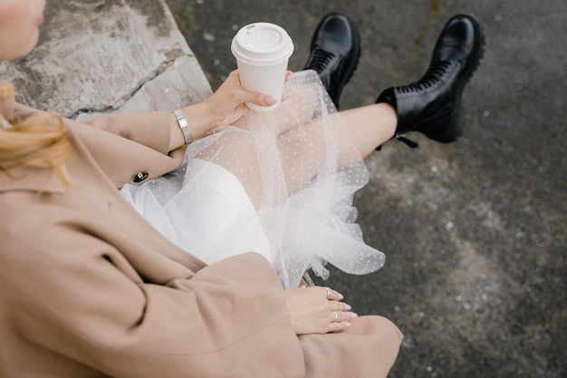 Chica elegante sentada con vasos de papel desechables con café