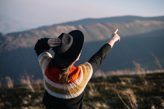 Chica elegante con sombrero y muestra las montañas