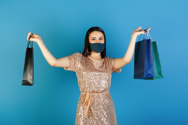 Chica elegante vestida hace compras con máscara protectora para la prevención del coronavirus Covid 19.