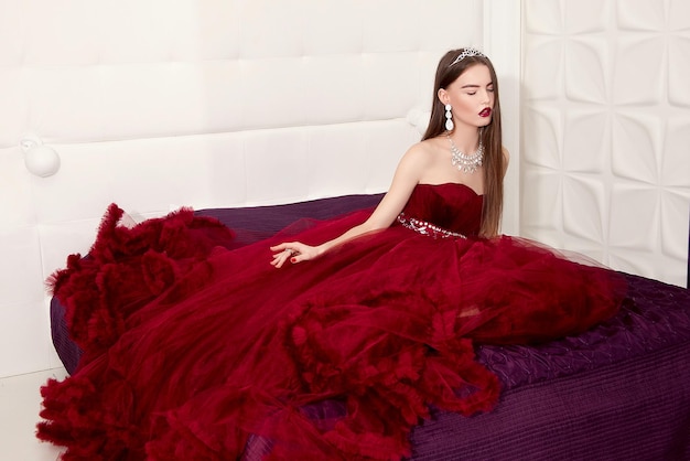 Foto una chica con un elegante vestido de fiesta de marsala en el contexto de un interior luminoso.