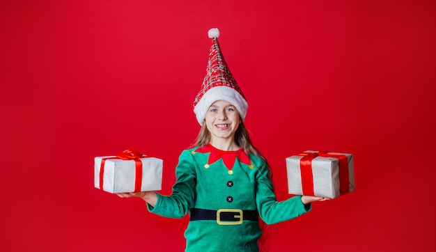 Chica elfa con regalos ayudante de Santa Claus sobre un fondo de color rojo brillante Copia espacio