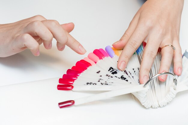 Foto la chica elige el color del polaco para la manicura. probadores de esmalte de uñas