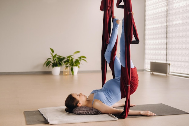Chica embarazada Una mujer hace yoga en una hamaca en el gimnasio El concepto de un estilo de vida saludable Maternidad