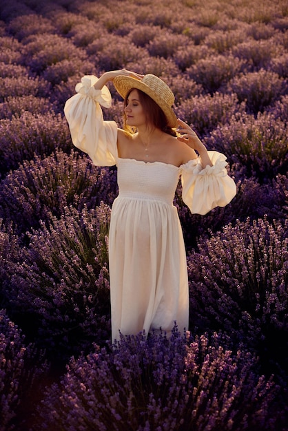 La chica embarazada con un sombrero en el campo de lavanda al atardecer