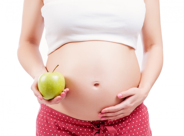 Chica embarazada sosteniendo una manzana verde