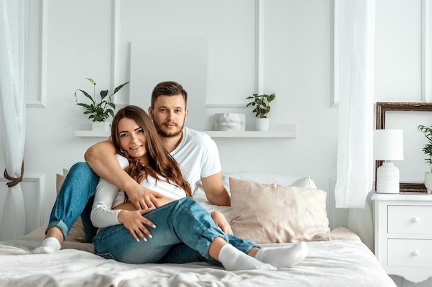 Chica embarazada con su marido se encuentran en la cama. Hermoso vientre de una joven atractiva embarazada. Concepto de familia, matrimonio, parto.