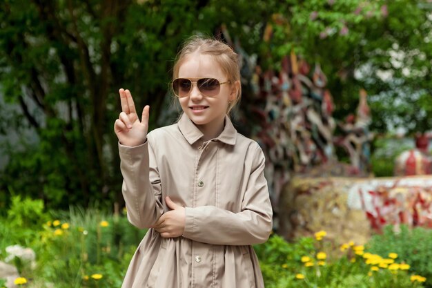 Chica de emoción adolescente feliz en ropa casual y gafas de sol en la calle de la ciudad