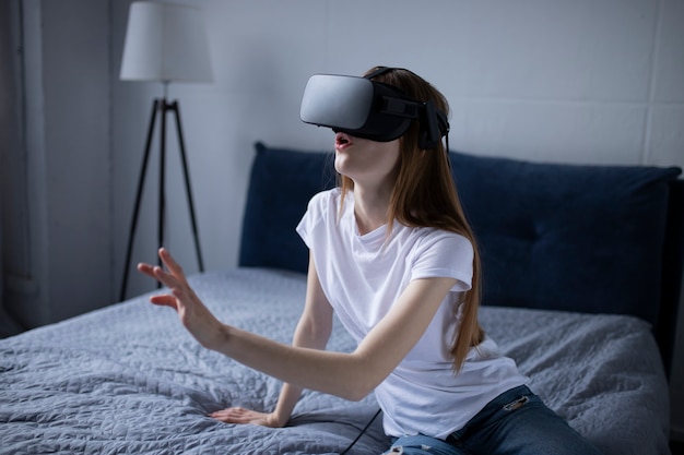 Chica emocionada en gafas de realidad virtual sorprendida. Ella está tocando algo y expresa las emociones de esta experiencia. Guau
