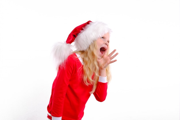 Chica emocional en Navidad Santa hat está parado con la boca abierta y gritando