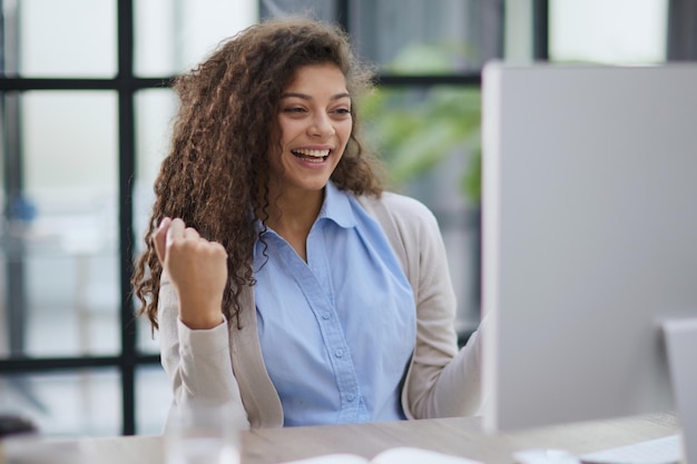 Foto chica emocional sorprendida al obtener la victoria en un concurso en línea leyendo noticias de una computadora portátil