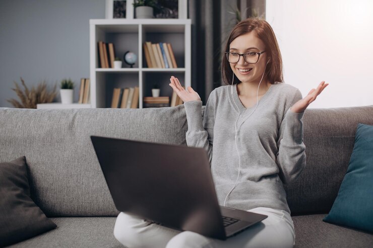 Chica emocional con video chat en la computadora portátil en casa