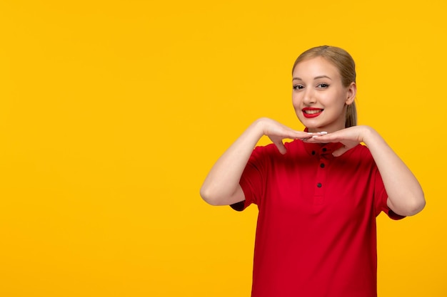 Foto chica encantadora del día de la camisa roja sonriendo con una camisa roja sobre un fondo amarillo