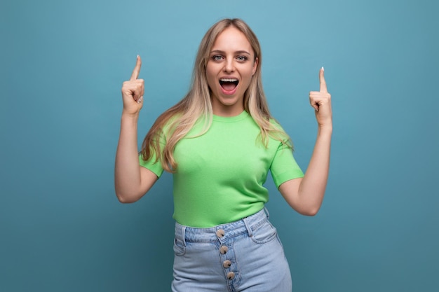 Chica enérgica con ropa informal gritando alegremente apuntando hacia el fondo azul