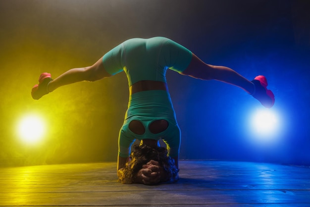 La chica entrena en un gimnasio moderno de fondo oscuro en un fondo azul amarillo con un lugar para el texto