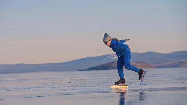 La chica entrena en patinaje de velocidad sobre hielo. El niño patina en invierno con traje deportivo azul, gafas deportivas. Deporte de patinaje de velocidad para niños.