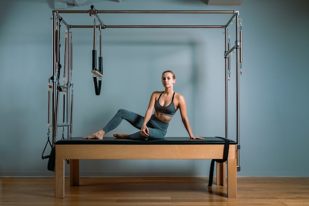 Chica de entrenador de paladares posando para un reformador en el gimnasio. Concepto de fitness, equipo de fitness especial, estilo de vida saludable, plástico. Copia espacio, banner deportivo para publicidad.