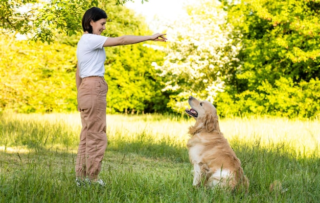 Chica entrenando perro golden retriever al aire libre