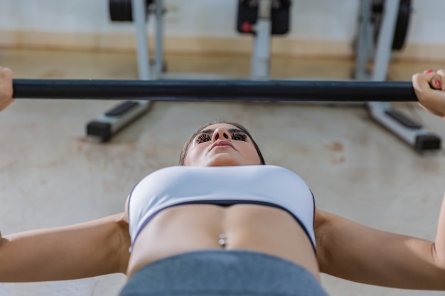 Chica entrenando con press de banca en un gimnasio