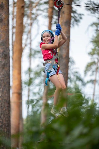 Chica en equipo supera un obstáculo en un parque de cuerdas a una altura