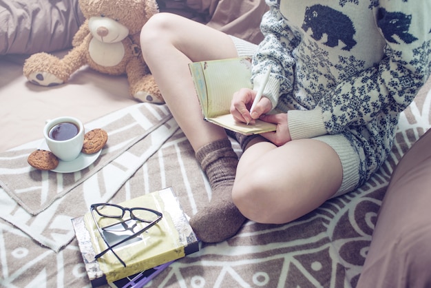 Chica escribiendo en un cuaderno sentado en la cama