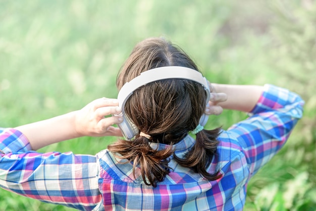 Chica escuchando música con auriculares en el céspedChica escuchando música con auriculares en el césped