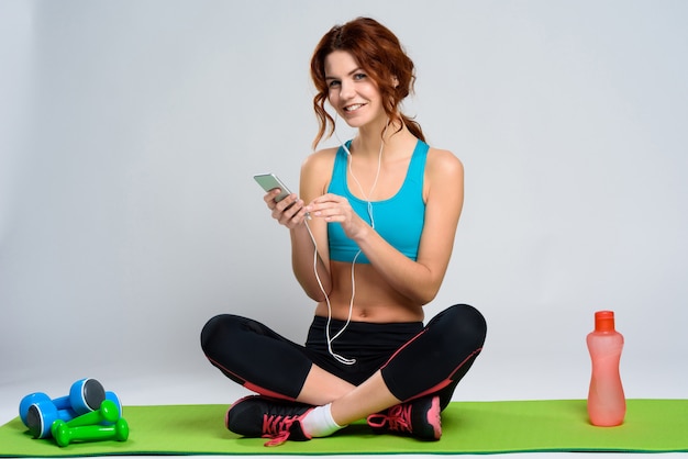 Chica Escuchar Música Con Auriculares En La Alfombra De Gimnasio.